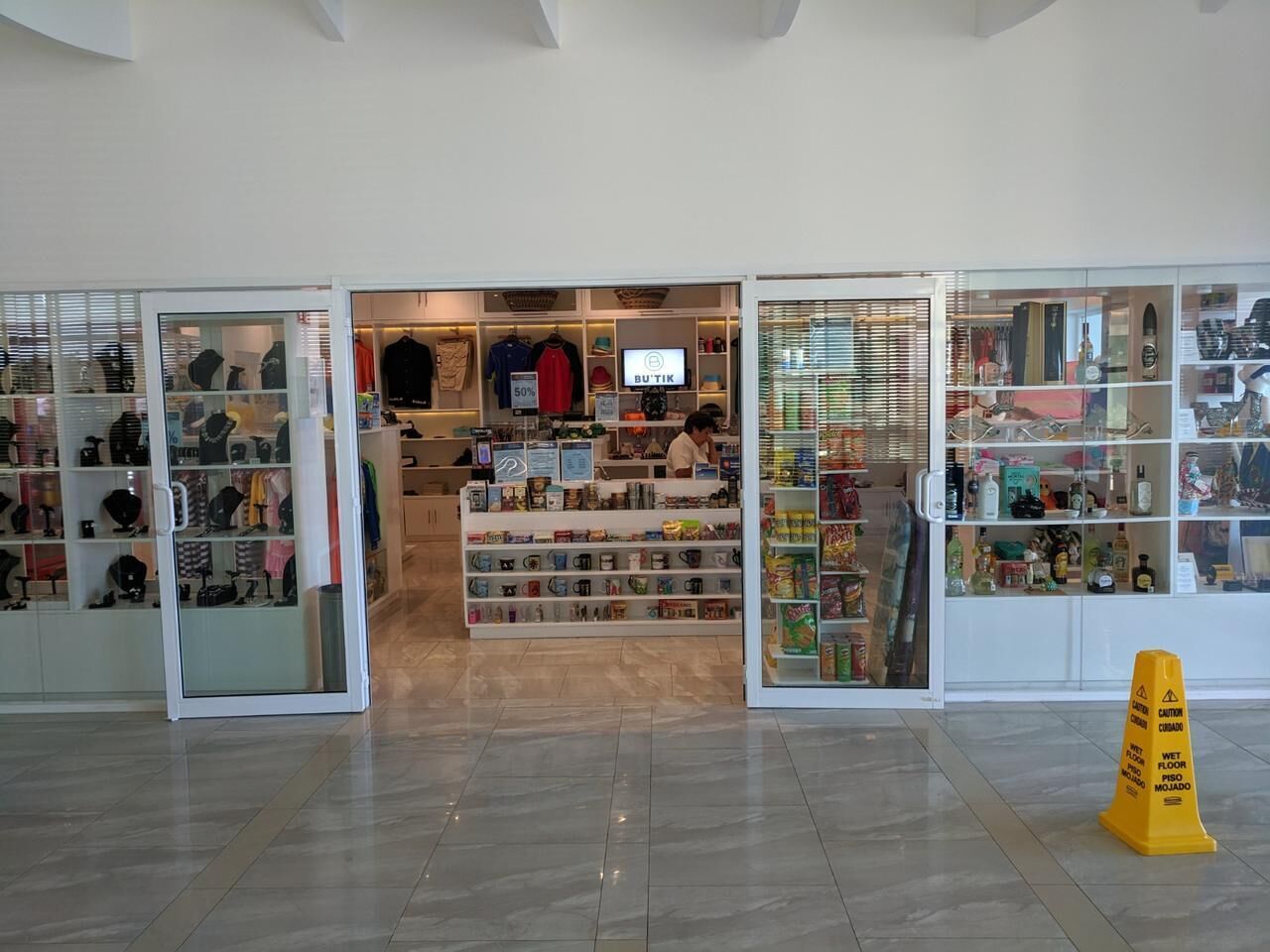 A store with glass display cases and a wet floor sign.