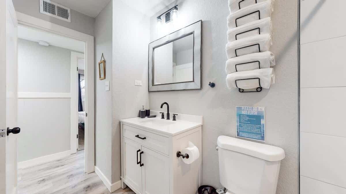 A bathroom with a toilet, sink, mirror, and towel rack.