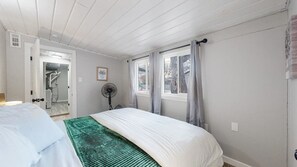 A bedroom with a bed, a fan, a window with curtains, and a door leading to a bathroom. - Modern Family Home with Three King Beds Near VA & Anschutz (Aurora)