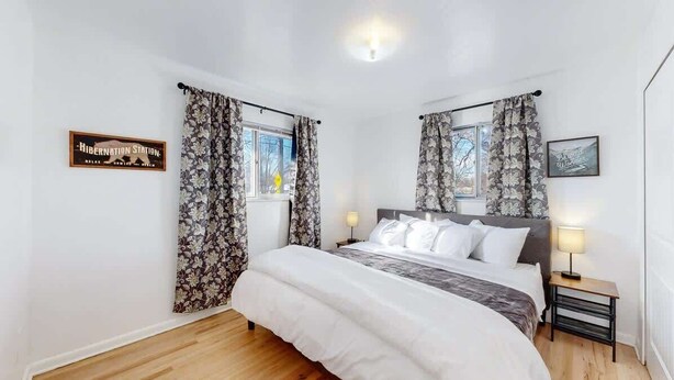 A bedroom with a bed, two bedside tables, a window with curtains, a wall-mounted sign, and a picture frame. - Spacious Arvada Home with King Beds and Office (Arvada)