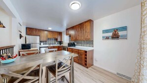 A modern kitchen with wooden cabinets, a dining table, and a large window. - Spacious Arvada Home with King Beds and Office (Arvada)