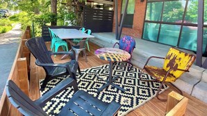 Un espace extérieur aménagé avec des bancs et des chaises en bois, une table et un tapis à motifs.