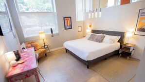 Une chambre à coucher avec un lit, des tables de chevet, un bureau et une chaise.