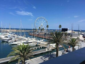 A marina with numerous boats docked, a large Ferris wheel, and palm trees. - Fully furnished ground-floor T2 apartment in Port de Canet-en-Roussillon, near the beach. (Canet-en-Roussillon)