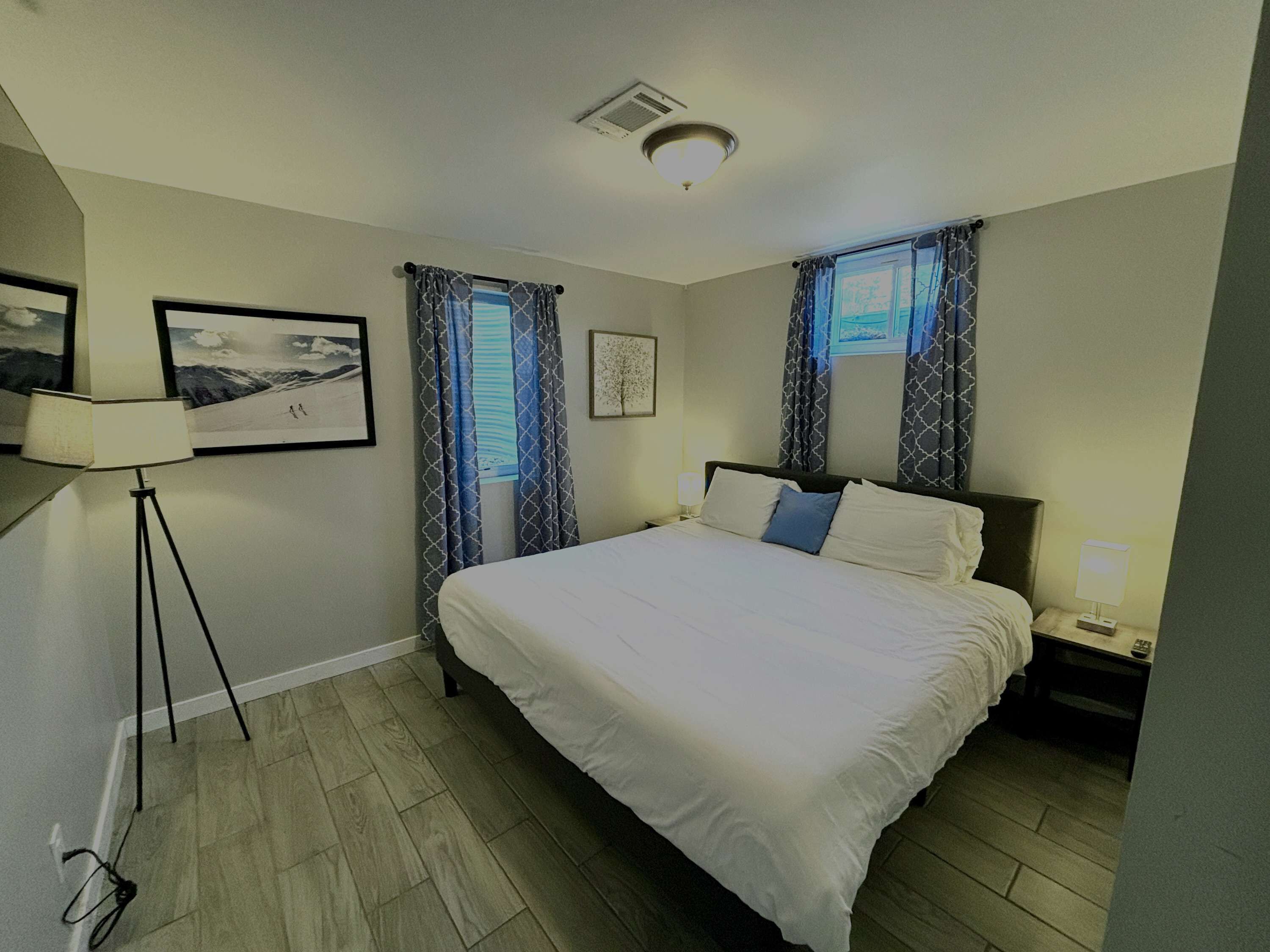A hotel room with a large bed, a desk, a chair, a lamp, and a picture on the wall.
