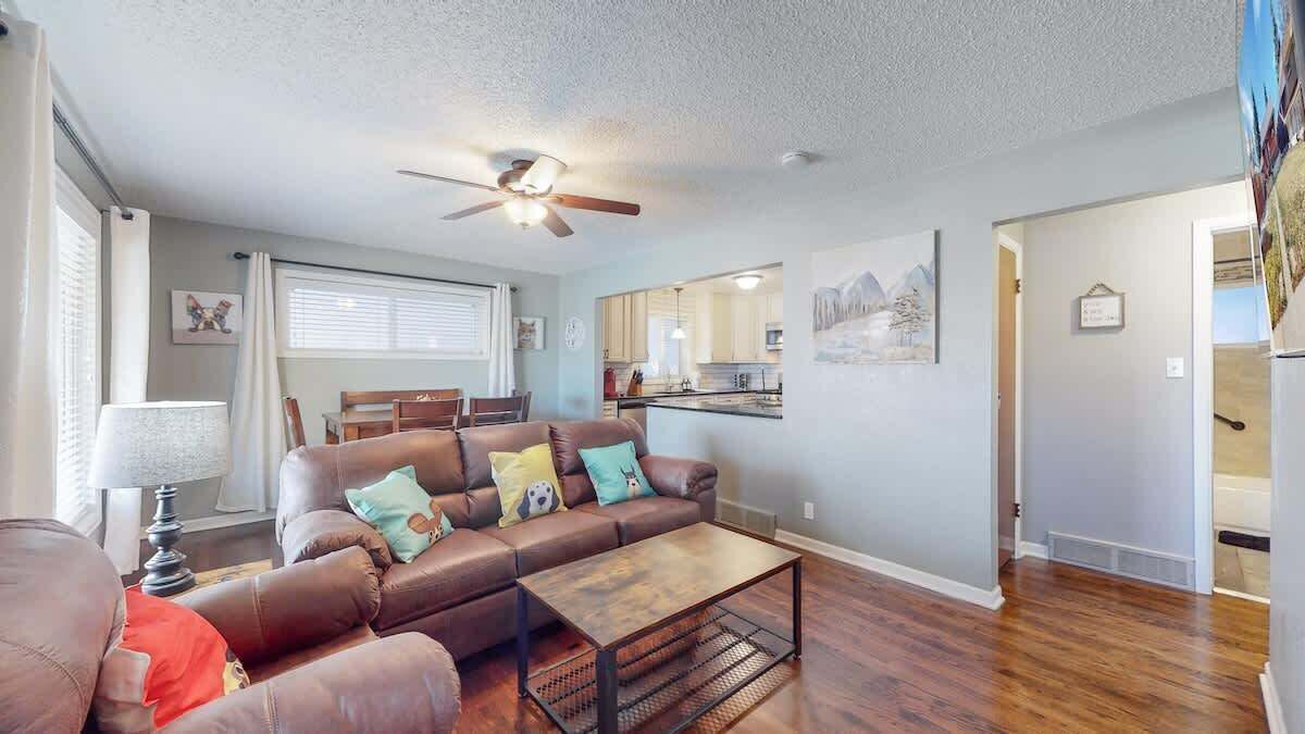 A living room with a brown leather sofa, a wooden coffee table, and a ceiling fan.