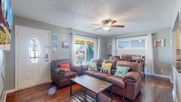 A living room with a brown leather sofa, a coffee table, and a ceiling fan.