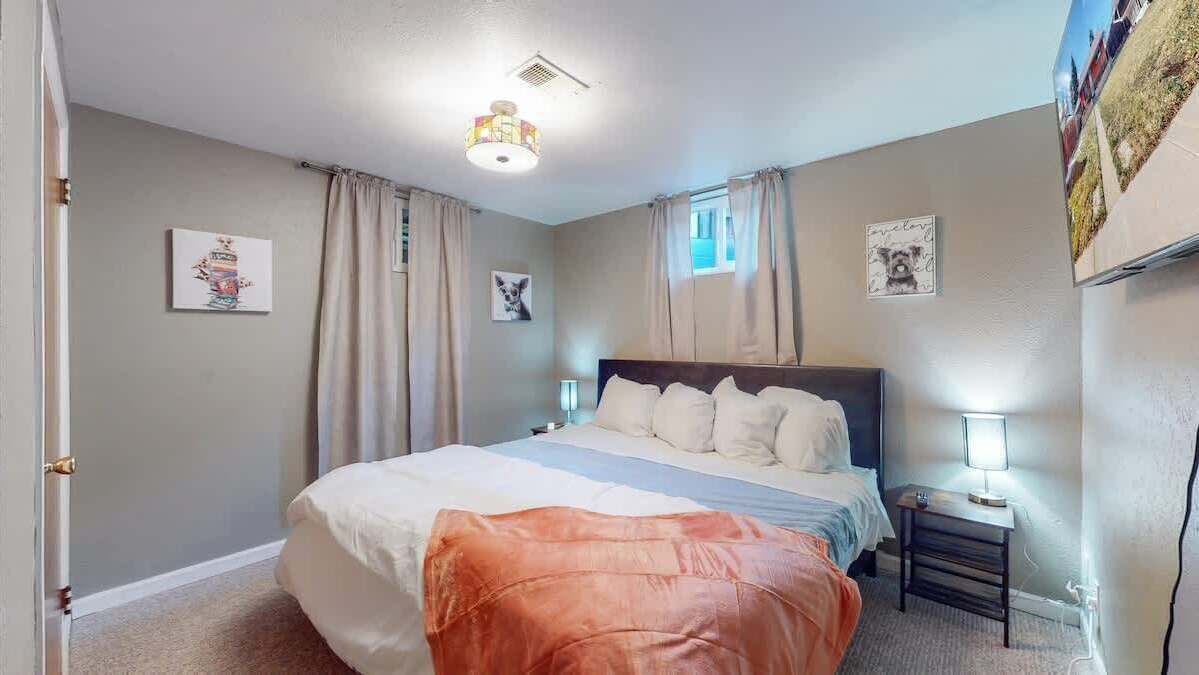 A bedroom with a bed, bedside lamps, and curtains.