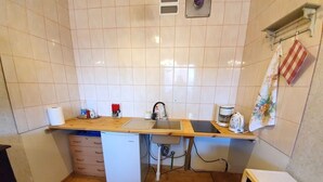 Eine kleine Küche mit Holzausziehtisch, Spüle, kleinem Kühlschrank und Mikrowelle.