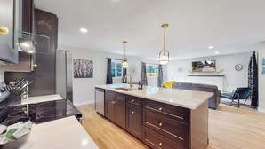 A modern kitchen with a central island, dark cabinetry, and stainless steel appliances. - Spacious Family Retreat in Denver (Denver)