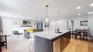 Uma cozinha moderna com ilha central, eletrodomésticos embutidos e iluminação pendente.