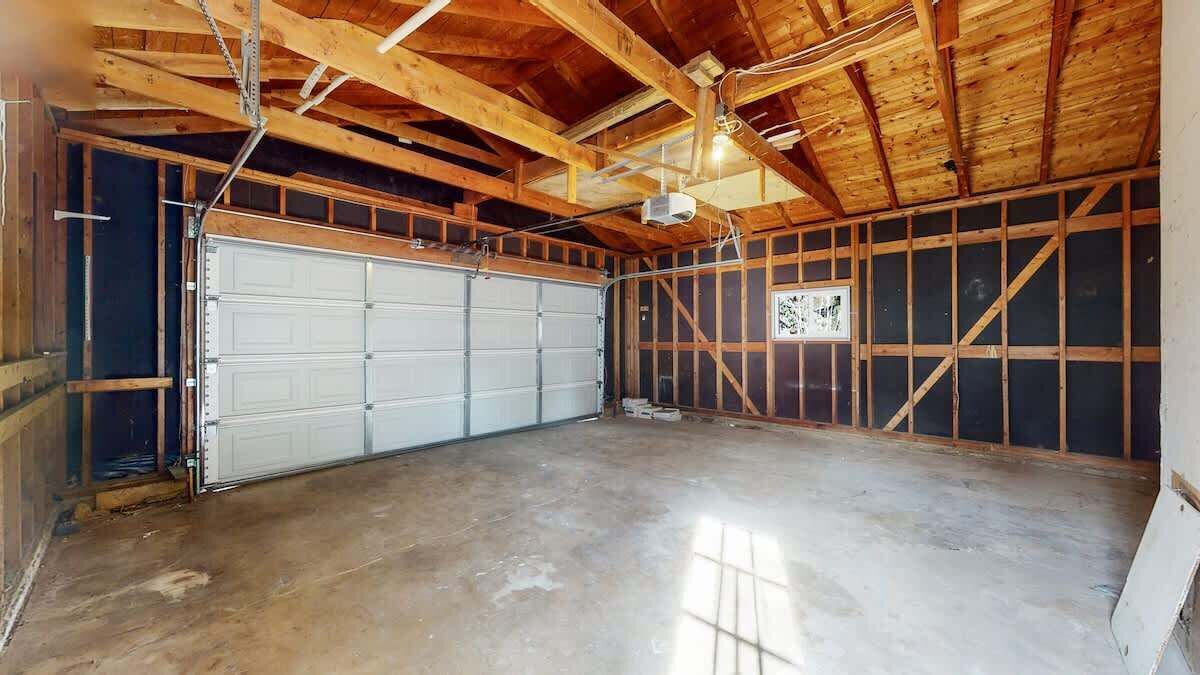 Un grand garage doté d’un sol en béton et de poutres en bois au plafond.