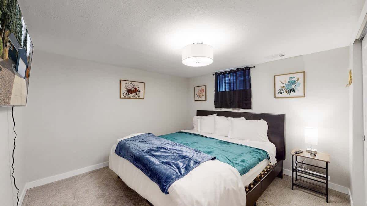A bedroom with a bed, a bedside table, and a wall-mounted TV.