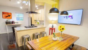Cozinha moderna com ilha central, banquetas de bar e mesa de jantar com um vaso de girassóis.