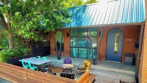 A patio area with a wooden deck, outdoor seating, and a blue door with the number 3799.