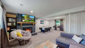 Una sala de estar con chimenea, mesa de billar, sofá y televisor.