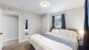 Une chambre à coucher avec un grand lit, une table de chevet, une fenêtre avec des rideaux et une porte.
