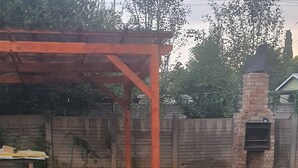 Ein Hinterhof mit Pflasterterrasse, einem Holztisch, einem Ziegelbarbecue und einem Ziegelofen.