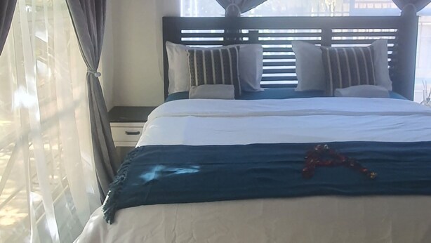 Ein Schlafzimmer mit Bett, Vorhängen, Fenster und Nachttisch.