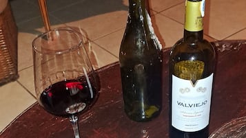 A table with a bottle of wine, a glass of red wine, and a plate of food.