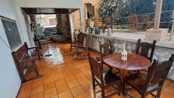 Un patio con una mesa redonda de madera y sillas, una escalera de piedra y varios muebles de madera.