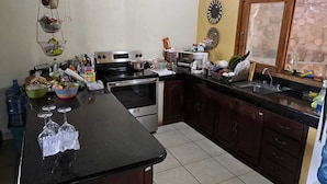 A kitchen with a large island, a stove, a microwave, and various kitchen items. - Villa Chelsey (Valle de Angeles)