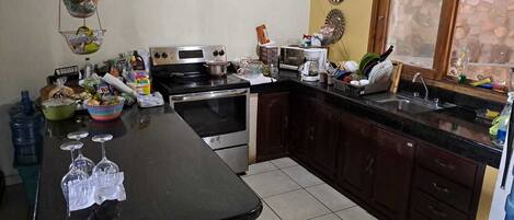 A kitchen with a large island, a stove, a microwave, and various kitchen items.