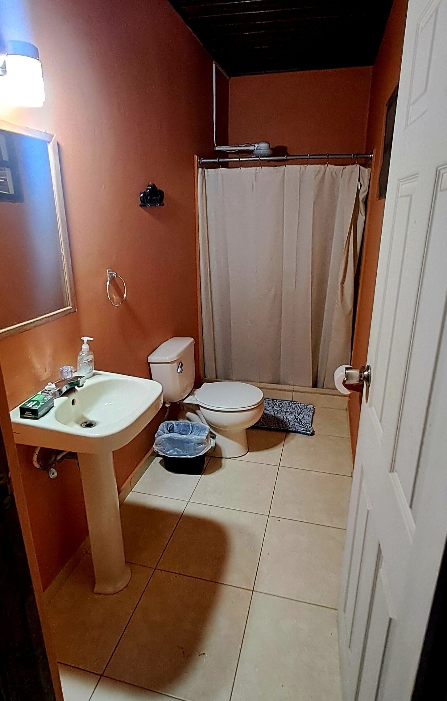 A compact bathroom with a sink, toilet, and shower curtain.