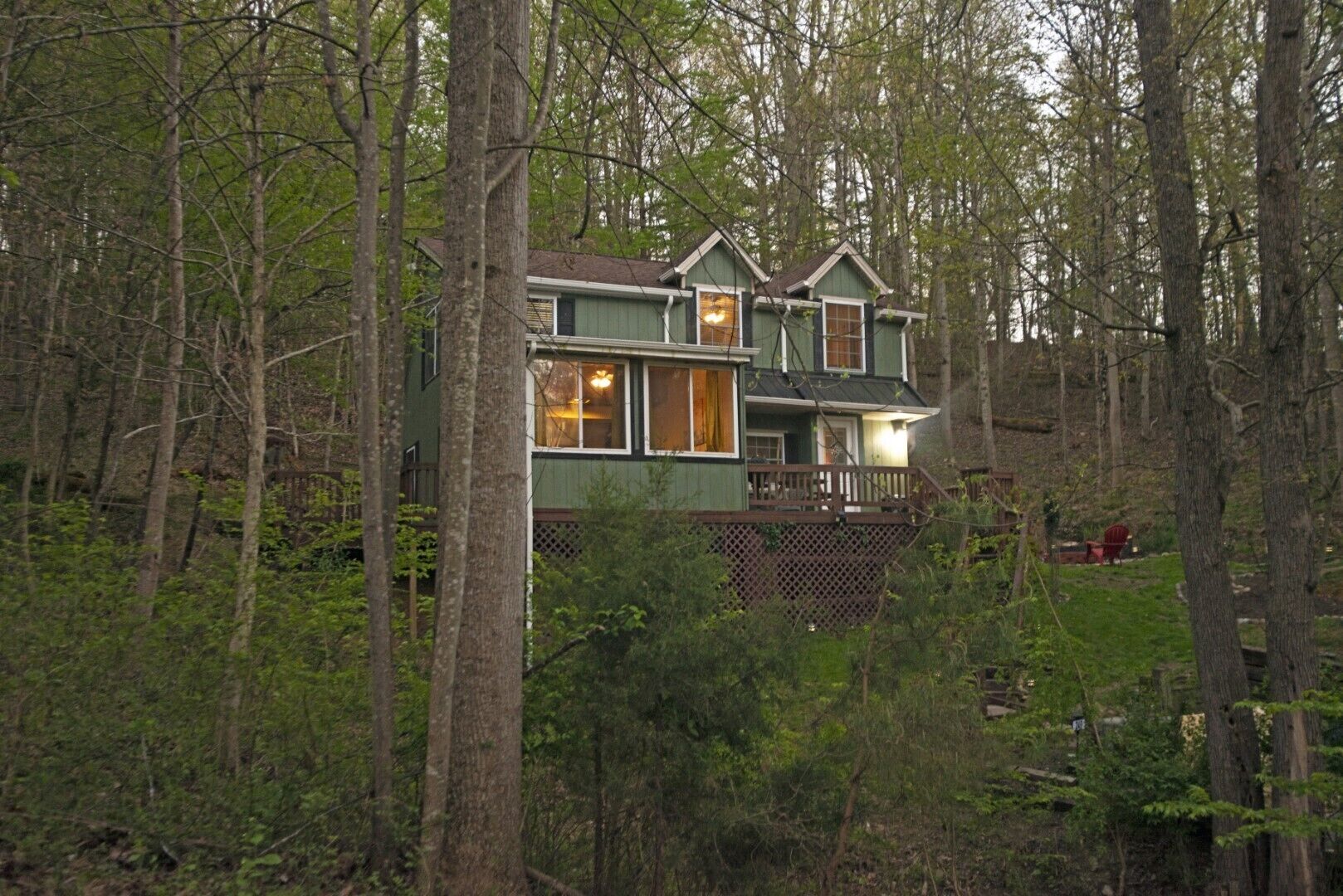 A two-story house surrounded by dense forest.