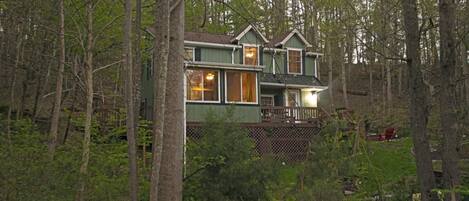 A two-story house surrounded by dense forest.