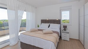 Une chambre à coucher avec un lit, une table de chevet, une lampe et une fenêtre donnant sur un paysage verdoyant.
