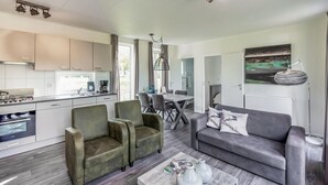 A modern living room with a grey sofa, green armchairs, and a coffee table. - Nice home in Zorgvlied with WiFi (Zorgvlied)