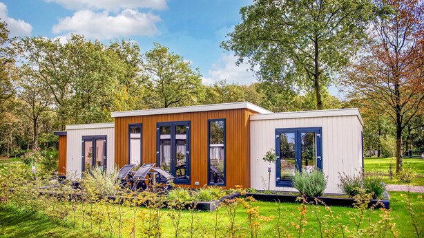 A modern, single-story cabin with large windows and a wooden facade, surrounded by a well-maintained garden and trees. - Nice home in Zorgvlied with WiFi (Zorgvlied)