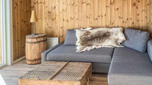 A room with a grey sofa, a wooden barrel, a woven coffee table, and a fur rug. - Stunning home in ålen (Ålen)