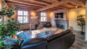 Un salon chaleureux avec une cheminée, un canapé en cuir et une table basse.