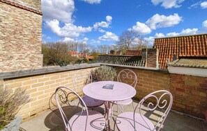 A patio with a round table and four chairs, a brick wall, and a tiled roof in the background. - Amazing home in Damme with WiFi (Damme)