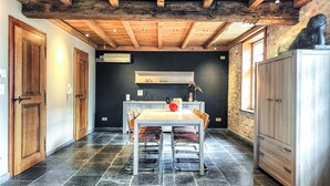 Une cuisine rustique avec un plafond en bois, un mur noir et un sol carrelé.