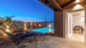 A pool area with stone walls, lounge chairs, and a table with chairs. - Luxurious home in Benkovac (Benkovac)