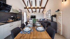 A modern kitchen with a dining area, wooden beams, and a stone wall. - Luxurious home in Benkovac (Benkovac)