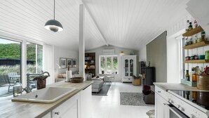 Una cucina moderna con mobili bianchi, una grande isola e un piano cottura integrato.