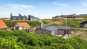 Una zona residenziale costiera con case moderne, alcune dotate di ampie vetrate e altre con tetti piani.