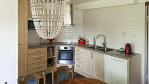A kitchen with white cabinets, a stainless steel oven, a dishwasher, and a red kettle.
