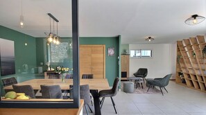 Relax in this stylish living space with a large dining table, comfortable seating area, and shelving unit.