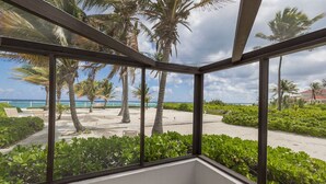 Una stanza con ampie finestre vista spiaggia, palme e piscina.