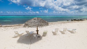 Una spiaggia con un ombrellone di paglia e diversi lettini.