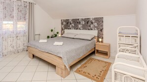 A bedroom with a wooden bed, a nightstand, a wicker chair, and a patterned wall. - 1 bedroom cozy apartment in Vir (Vir)