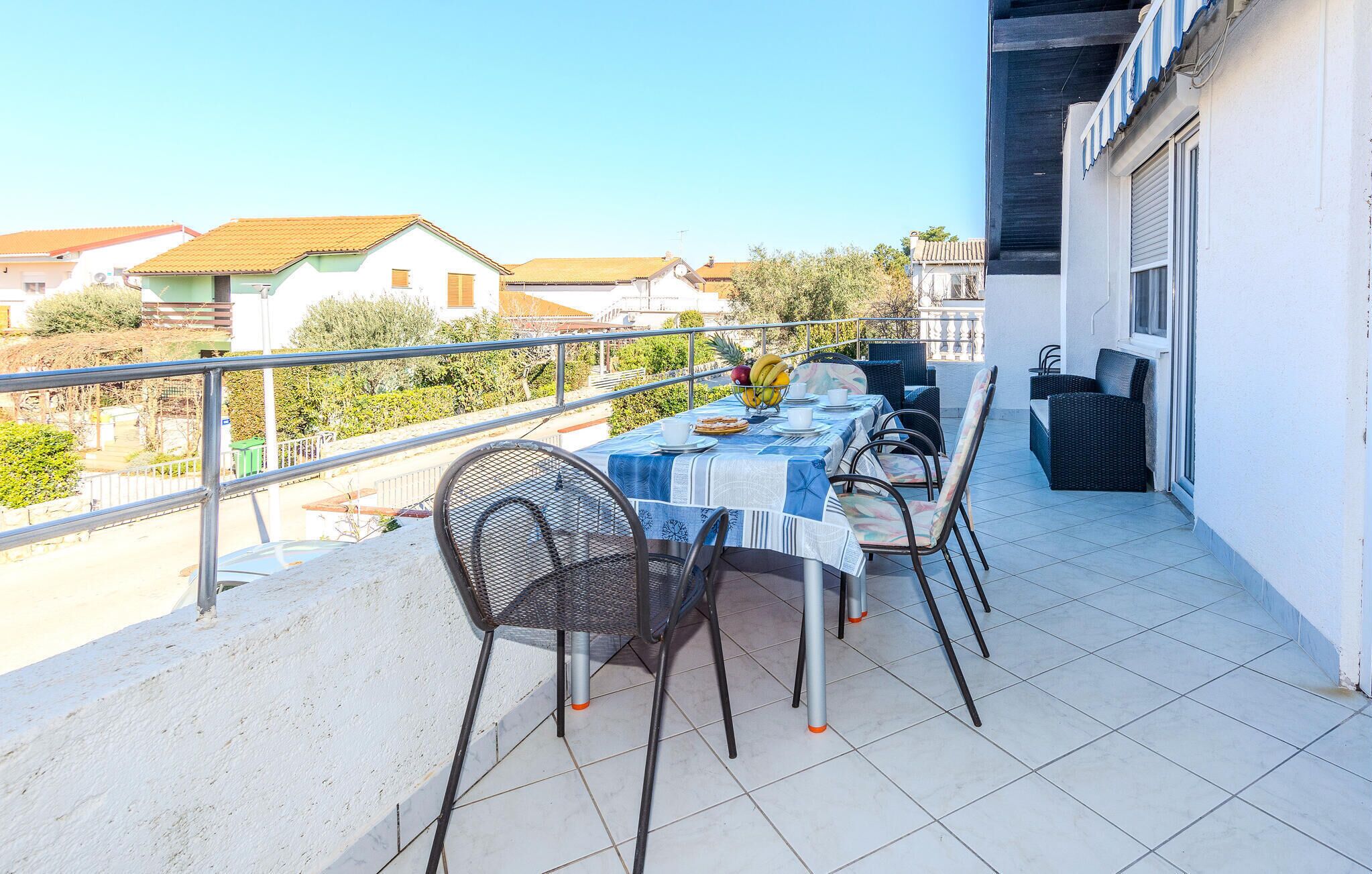 A balcony with a table set for two, chairs, and a small fruit bowl.
