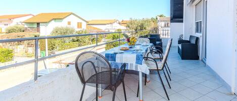 A balcony with a table set for two, chairs, and a small fruit bowl.