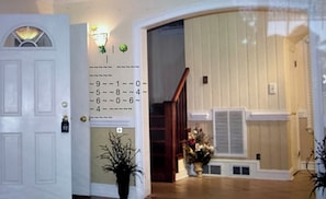 A hallway with a white door, a wall-mounted number keypad, and a staircase leading to another room.