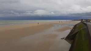 Una playa con una barrera de hormigón, algunas personas y un cielo nublado.